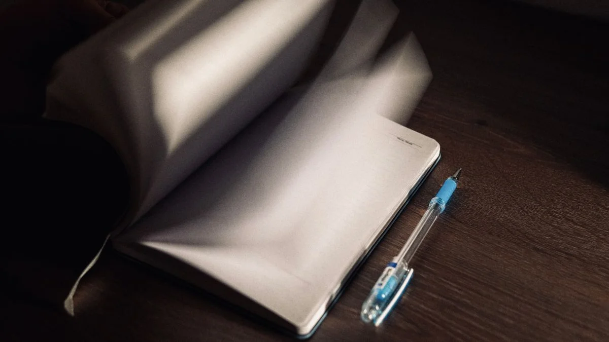 An open notebook and pen on a wooden desk, ready for a gratitude entry