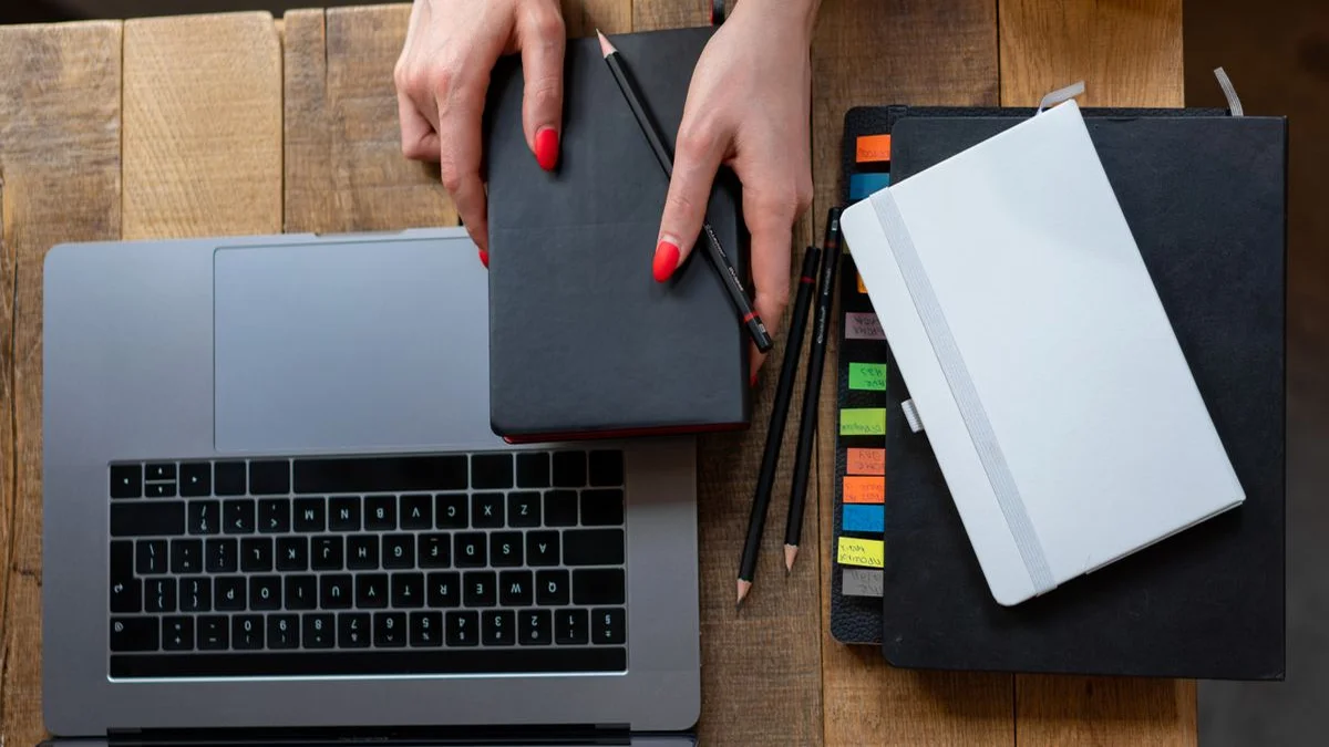 Leather-bound notebooks and a laptop glowing on a wooden desk, representing decades of marginal notes preserved offline