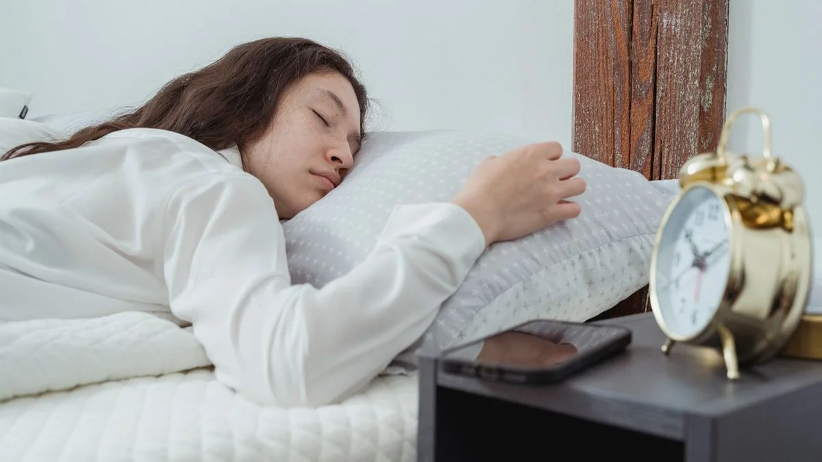 Person sleeping with a phone playing forest sounds on a bedside table